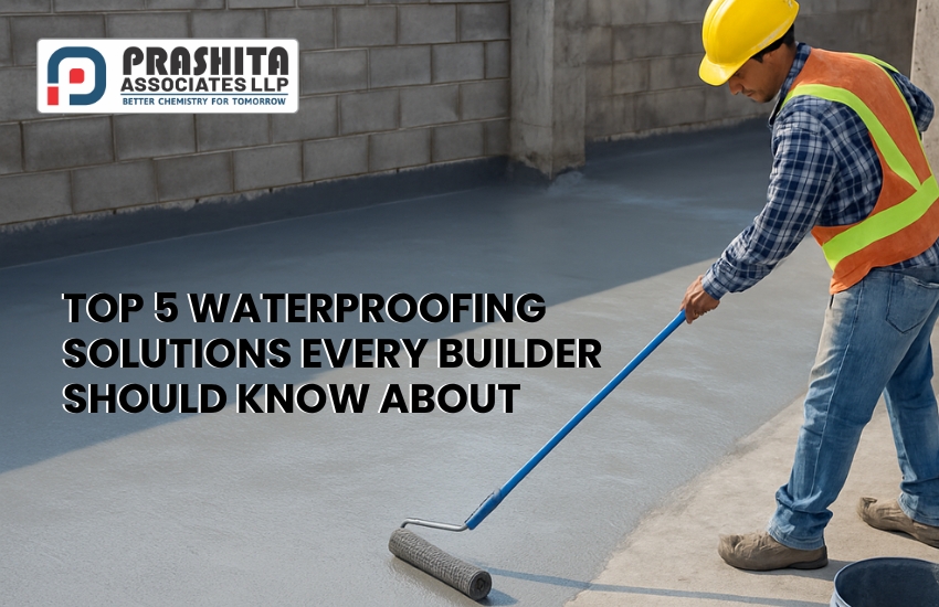 A construction worker in a yellow hard hat and reflective vest is applying a grey waterproofing coating on a concrete floor using a long-handled roller. The Prashita Associates LLP logo appears in the top-left corner, along with the text: “Top 5 Waterproofing Solutions Every Builder Should Know About.